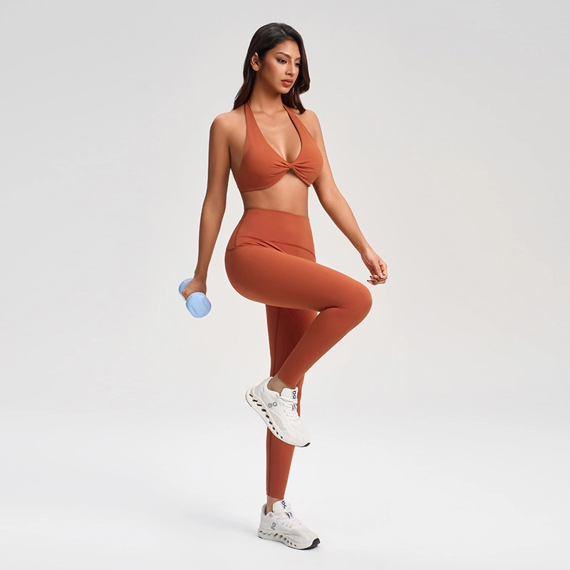 Custom Halter Deep V-Neck Sports Bra – Twist Front | MZ-1005 5 Model doing dumbbell workout in muzyoga rust orange sports bra and legging set.