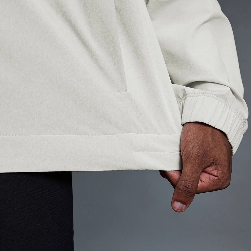 MZ-MJ003 | Wholesale Men's Ultra-Light Windbreaker: 145G High-Performance Fabric & Underarm Ventilation - Bone White - muzyoga 6 Detailed view of the elasticized hem for wind protection.
