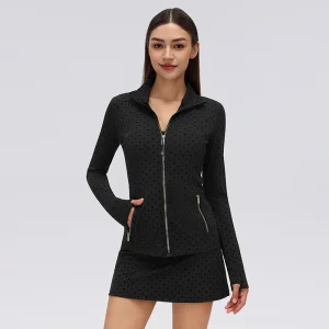 Front view of a fitted black flocked polka dot workout jacket with a stand collar, gold-tone front zipper, zippered side pockets and thumbhole sleeves.