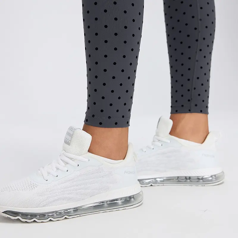 Women's High-Waisted Flocked Polka Dot Leggings 5 Close-up of the ankle-length hems on Gray polka dot leggings, showing the fitted lower legs and neatly stitched fabric edges.