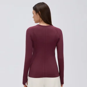 Back view of a woman wearing a Burgundy seamless long sleeve workout top, showing the fitted silhouette and vertical textured knit panels.