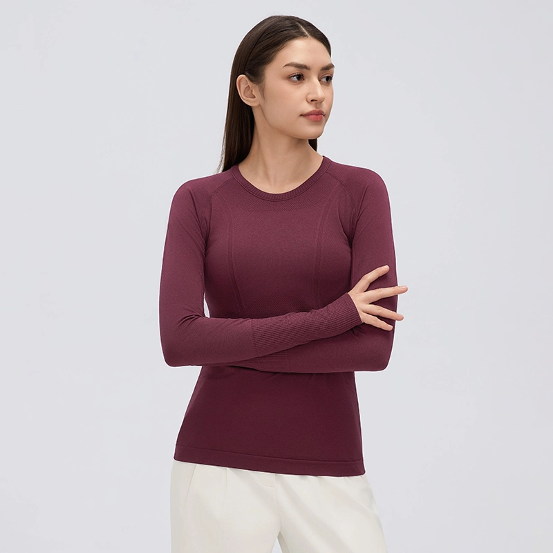 Women's Seamless Long Sleeve Workout Top with Thumbholes 1 Woman wearing a burgundy seamless long sleeve workout top with a crew neck, fitted shape and textured knit panels.