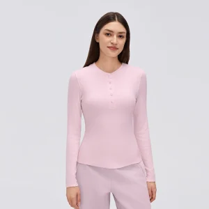 Front view of a model wearing a pearl pink women's ribbed modal Henley long sleeve top with a button placket and curved hem.