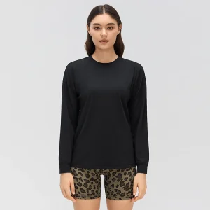 Front view of a women's black crew neck long sleeve yoga top with dropped shoulders, a relaxed fit and banded cuffs.