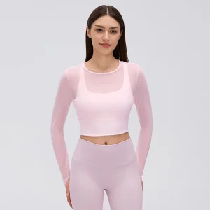 Front view of a model wearing a Pearl Pink mesh long sleeve workout top with a round neckline, built-in bra and fitted cropped hem.