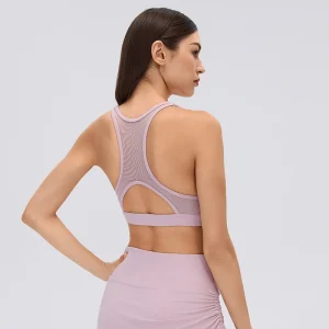Rear three-quarter view of a Porcelain Pink sports bra featuring a breathable mesh racerback panel, arched back cutout and wide shoulder straps.