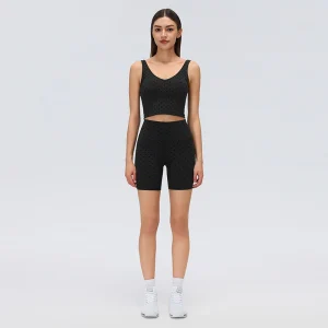 Front view of black high-rise flocked polka dot biker shorts with a wide waistband and fitted mid-thigh legs, worn with a matching workout top.