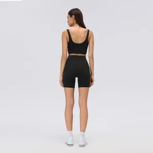 Rear view of black flocked polka dot workout shorts with a high-rise waistband, curved back panel seams and fitted mid-thigh length.